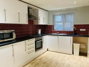 a kitchen with white cabinets and black counter tops at Cosy home near hospital in Carlisle