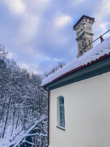 a house with a chimney and snow on the roof at Krioklio Namelis Verkiuose in Vilnius