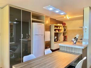 uma cozinha com um frigorífico, uma mesa e cadeiras em Apartamentos Lagos de Gramado by Achei Gramado em Gramado