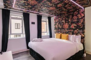 ロンドンにあるWelcomeStay Fitzrovia Two Bed Apartments - Sleep in Opulent Luxuryの花柄の壁紙を用いたベッドルーム1室(大型ベッド1台付)