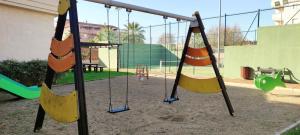an empty playground with two swings and a swing at Apartamento TomCar Piscina, Pádel, wifi y zonas comunes in Sanlúcar de Barrameda
