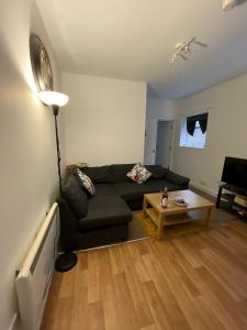 a living room with a black couch and a table at Spacious sofa bed lounge area with ensuite bedroom in Wednesbury