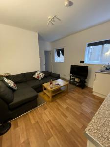 a living room with a black couch and a piano at Spacious sofa bed lounge area with ensuite bedroom in Wednesbury
