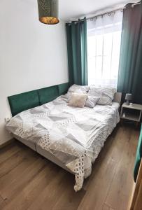 duże łóżko w sypialni z zielonymi zasłonami w obiekcie Apartament Olecko Centrum w mieście Olecko