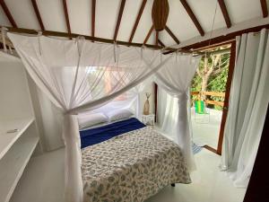 a bedroom with a canopy bed with a window at Casa do cajueiro in Praia do Espelho