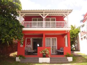 uma casa vermelha com uma varanda branca no topo em Colibri Beach Villas em Trou dʼ Eau Douce