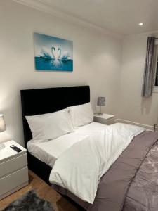 a bedroom with a large bed with white sheets at Beautiful 3 Bedrooms town house with parking in Redbridge