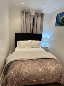 a bedroom with a large bed with a black headboard at Beautiful 3 Bedrooms town house with parking in Redbridge