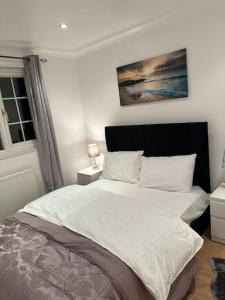 um quarto com uma cama grande e lençóis brancos em Beautiful 3 Bedrooms town house with parking em Redbridge