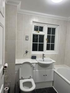 a white bathroom with a toilet and a sink at Beautiful 3 Bedrooms town house with parking in Redbridge