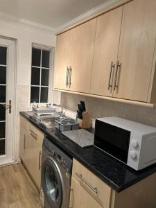 a kitchen with a washing machine and a microwave at Beautiful 3 Bedrooms town house with parking in Redbridge