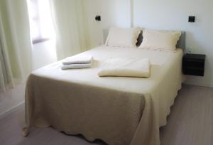 ein weißes Bett mit zwei Handtüchern darauf in der Unterkunft Casa no Caravaggio ao lado da cervejaria 3 Santas in Santa Teresa