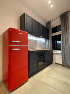 a kitchen with a red refrigerator and black cabinets at BISCHOFSBERG Gdańsk City Center Apartments in Gdańsk