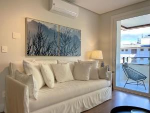 a white couch in a living room with a window at Apartamentos L'adress Reserve CENTRO by Achei Gramado in Gramado