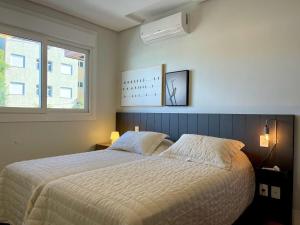 um quarto com uma cama grande e uma janela em Apartamentos L'adress Reserve CENTRO by Achei Gramado em Gramado