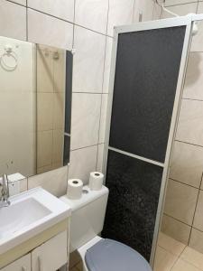 een badkamer met een toilet, een wastafel en een spiegel bij Hotel Paradyse Praia in Capão da Canoa