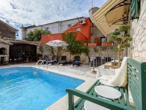 a swimming pool with chairs and an umbrella next to a building at Casa Antignana in Tinjan