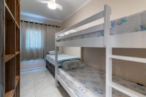 a bedroom with two bunk beds and a window at Apê Aconchegante Canto do Forte e Boqueirão em Praia Grande in Praia Grande