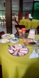 einem Tisch mit Lebensmittelplatten auf einem gelben Tischtuch in der Unterkunft Golden waters Lodges in Iquitos