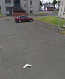 a white arrow in a parking lot with a red car at Modern flat in Jerviston Court in Motherwell