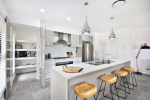 a kitchen with white cabinets and a counter with stools at Rockwall I Pet Friendly I Fire Pit in Bundanoon