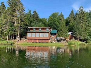 a large house sitting on the side of a lake at Middle Pond Cabin- Direct ATV & Snowmobile Access in Pittsburg