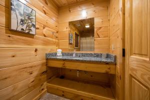 a bathroom with a sink in a wooden cabin at Mountain Retreat 5b5b Cabin with 2 HotTubs, Theater & Game Rm,1mi to the Parkway! - Ideal for Family Reunions or Group Getaways! Home away from home in Pigeon Forge