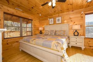 a bedroom with a bed in a log cabin at Mountain Haven with 2 HotTubs, Thtr &Game Rm, Summer Special,1mi to the Parkway! - Ideal for Family Reunions or Group Getaways! Home away from home in Pigeon Forge
