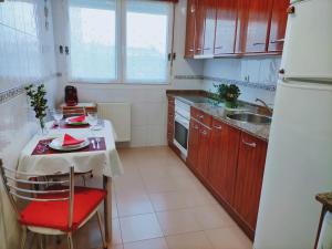 een kleine keuken met een tafel met een rode stoel bij Apartamento de 2 hab. con todo lo necesario. in Gijón