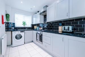 a kitchen with white cabinets and a washer and dryer at West Midlands 3 Bed! Sleeps 5! Perfect for Contractors and Groups! FREE OFF STREET PARKING! 2 Bathrooms! FREE WIFI! Ideal for Long Stays in Ocker Hill