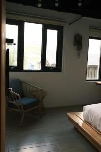 a bedroom with a bed and a chair and windows at Summer Delight B&B in Nanwan
