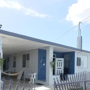 ein blaues Gebäude mit einer Veranda und einer Hängematte vor dem Haus in der Unterkunft Casa Amalia Beach House in Aguada