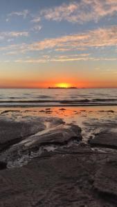 um pôr-do-sol numa praia com o oceano e o céu em CASA ARENA en la Rambla, frente a la playa ,para 4 personas em Colônia do Sacramento