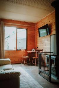 sala de estar con TV, mesa y sillas en Three Little Pigs Escape - Main House + Cabin, en South Bruny