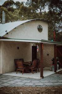 un patio con mesa y sillas frente a una casa en Three Little Pigs Escape - Main House + Cabin, en South Bruny