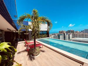 uma piscina no telhado de um edifício com uma palmeira em Edifício SKY Apto 810 - ER Hospedagens em Maceió