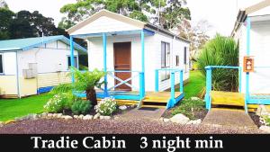 a small blue and white house with a porch at Strahan Retreat Holiday Park in Strahan