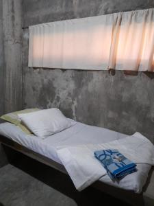 uma cama com lençóis brancos e uma janela em DUMA HOSTEL em Dumaguete