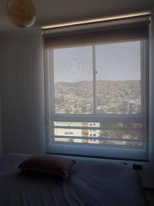 Un dormitorio con una ventana con vista a una ciudad. en Departamento Familiar Exclusivo 3D, en Valparaíso 10 fotos más