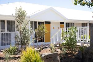 a small white house with a yellow door and windows at Sunnymead Hotel in Aireys Inlet