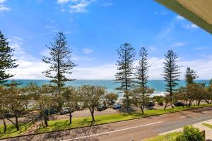 a view of a road with trees and the ocean at Seapoint Unit 14 32 Victoria Tce Kings Beach in Caloundra
