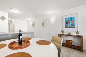 a dining room with a table with a bottle of wine on it at Seapoint Unit 14 32 Victoria Tce Kings Beach in Caloundra