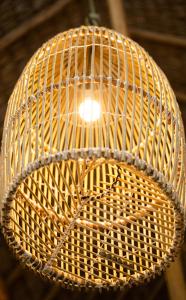 a wicker light fixture hanging from a ceiling at Jandaia Atins in Atins