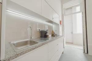 uma cozinha branca com um lavatório e uma janela em Porto Downtown Apartments by Vacationy no Porto