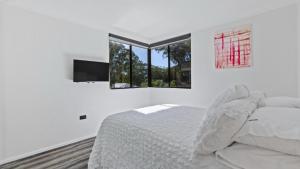 a white bedroom with a bed and two windows at Hawks Nest - Booner Street in Hawks Nest