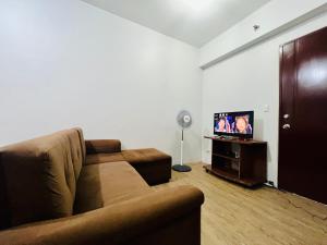 ein Wohnzimmer mit einem Sofa und einem Flachbild-TV in der Unterkunft At Home Condo With Free Pool Access in Manila