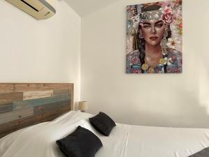 a bedroom with a white bed with a painting on the wall at DUCHARMOY LODGES in Saint-Claude