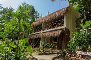 a resort building with a thatched roof and palm trees at Casa Lamat in Bacalar