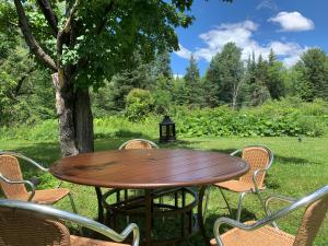 una mesa de madera y sillas bajo un árbol en Auberge Clos-Joli, en Morin-Heights