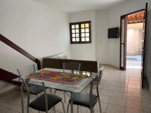 uma sala de jantar com uma mesa de vidro e cadeiras em Casa ao lado da praia em Barra de São Miguel